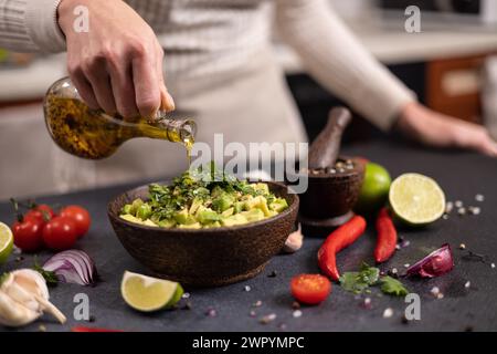 Cottura della salsa tradizionale - la donna versa l'olio d'oliva nel recipiente con ingredienti tagliati a fette Foto Stock