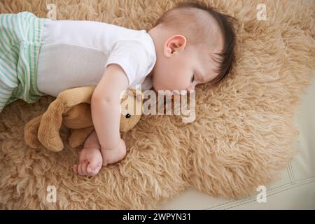 Bambino, dormi e casa con l'orsacchiotto nel divano per riposare, stanco e rilassarsi con il manichino e sognare. Angolazione elevata, bambino e lettino per lo sviluppo del bambino Foto Stock