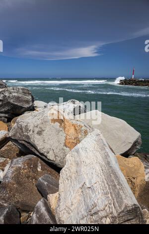 Grandi rocce e nuvole di tempesta minacciose nel cielo sopra l'acqua al frangiflutti sul fiume Wooli Wooli Foto Stock