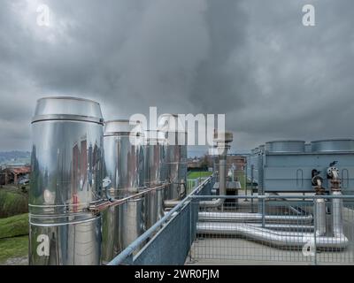 Camini in acciaio inox e scambiatori di calore di riscaldamento centralizzato e unità di climatizzazione installato sul tetto della struttura ospedaliera su cielo nuvoloso Foto Stock