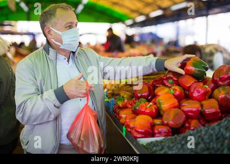 Uomo in maschera di faccia acquistare pepe in gregrocery Foto Stock
