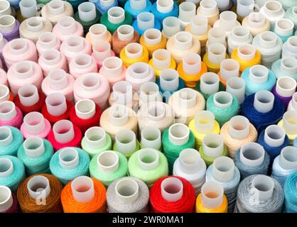 Filetto da cucire. Set di diversi fili da cucire colorati come sfondo, vista dall'alto Foto Stock