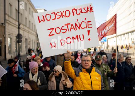 Un uomo ha un cartello con scritto "l'esercito polacco resta a casa" durante una manifestazione contro la guerra il 9 marzo 2024 a Varsavia, in Polonia. Diverse dozzine di persone hanno partecipato Foto Stock