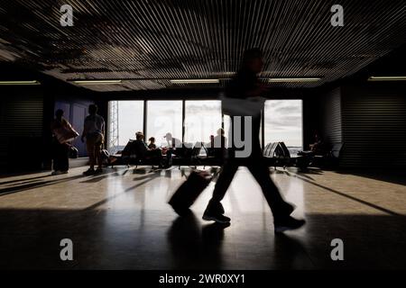 Passeggeri con bagagli che camminano lungo una sala di partenza vuota dell'aeroporto, foto di sfocatura con movimento manuale. Concetto di stile di vita in viaggio. Foto Stock