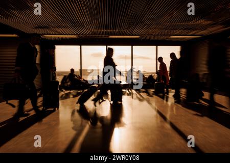 In attesa all'aeroporto, persone sedute e camminate con i bagagli attraverso l'area di partenza, foto di sfocatura del movimento. Viaggiatori e concetti di trasporto. Foto Stock