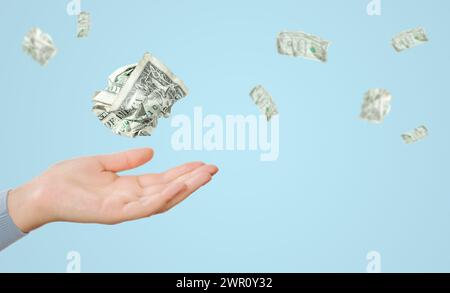 Le banconote da un dollaro volavano sopra la mano femminile su sfondo blu Foto Stock