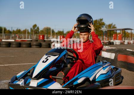 Il conducente si stacca dal casco protettivo mentre è seduto all'auto da corsa di kart Foto Stock