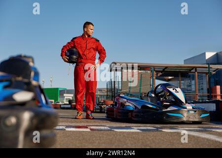 Pilota di go-kart che cammina fino all'auto prima di correre alla linea di partenza sul circuito automobilistico Foto Stock