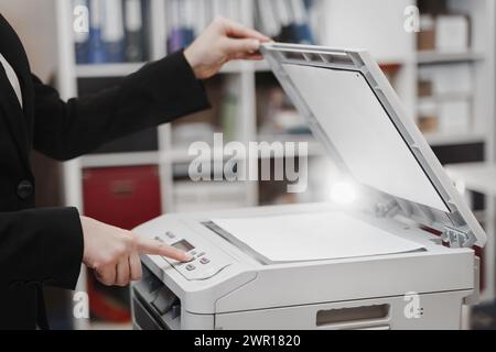 Bussinesswoman premere il pulsante a mano sul pannello della stampante, scanner stampante laser fotocopiatrice per ufficio concetto di avvio Foto Stock