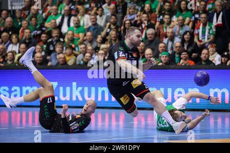 10 marzo 2024, Sassonia-Anhalt, Magdeburgo: Pallamano, Bundesliga, SC Magdeburg - Füchse Berlin, Matchday 25, GETEC Arena. Lukas Mertens (centro) di Magdeburgo lancia al gol dell'avversario, mentre Tim Hornke (sinistra) di Magdeburgo e Mathias Gidsel di Berlino sono a terra. Foto: Ronny Hartmann/dpa Foto Stock