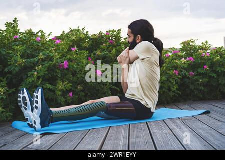 Amputato con protesi per le gambe che esegue un esercizio di stretching all'aperto - stile di vita attivo e fitness adattivo. Foto Stock