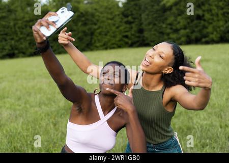 Le migliori amiche africane multirazziali catturano un gioioso momento di selfie all'aperto - celebrazione dell'amicizia immersa nel verde. Foto Stock