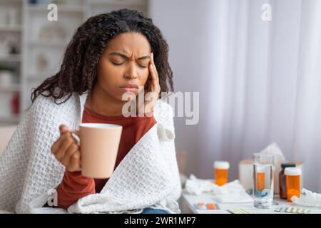 Giovane donna nera malata che soffre di mal di testa o freddo a casa Foto Stock