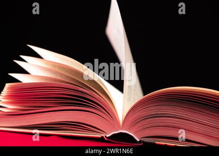 Le pagine di un libro spesso vengono attivate su uno sfondo rosa e nero Foto Stock