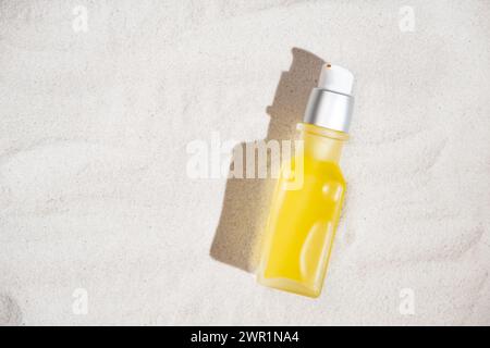 Olio cosmetico naturale in un vaso di vetro sulla sabbia, vista dall'alto, spazio di copia per il testo Foto Stock