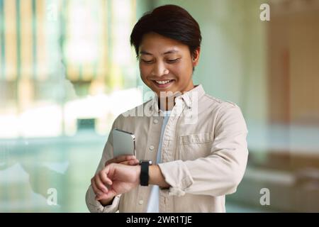 Sorridente asiatico con il telefono in mano che controlla il tempo Foto Stock