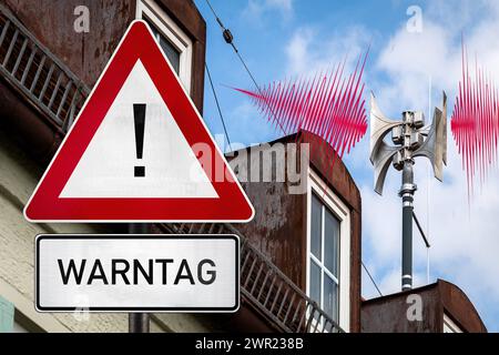 10 marzo 2024: Tetto della casa con una sirena di avvertimento e un cartello con un simbolo di attenzione, tema giorno di avvertimento 2024 giovedì 14.03.2024. FOTOMONTAGGIO *** Hausdach mit einer WARN-Sirene und einem Schild mit einem Achtung-Symbol, Thema Warntag 2024 AM Donnerstag, 14.03.2024. FOTOMONTAGE Foto Stock