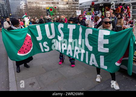 Londra, Regno Unito. 8 marzo 2024. Le donne prendono parte a un'azione della giornata internazionale della donna organizzata da gruppi tra cui i genitori per la Palestina, i genitori per il futuro Regno Unito, le famiglie della ribellione dell'estinzione e lo sciopero globale delle donne in solidarietà con le donne e i nascituri in Palestina. L'azione comprendeva un raduno di fronte al monumento commemorativo di Mary Seacole all'ospedale di St Thomas, un incontro di mani attraverso il ponte di Westminster e la posa di fiori su un gigantesco burattino incinta Mother Sunbird in Parliament Square. Crediti: Mark Kerrison/Alamy Live News Foto Stock