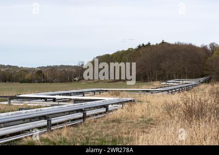 Tubazioni che attraversano un campo con erba secca gialla Foto Stock