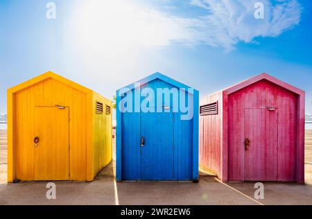 baite sulla spiaggia colorate di giallo, blu e rosa Foto Stock