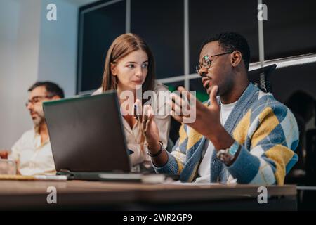 Colleghi di varie origini collaborano in una moderna sala conferenze, discutendo strategie aziendali, pianificazione dei progetti e offrendo supporto. Foto Stock