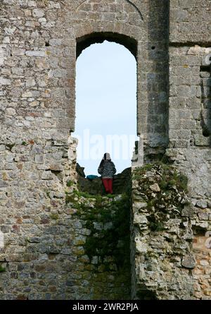 Una veduta di una giovane ragazza, che ha scavato le mura dell'antico castello medievale, per avere una splendida vista sulla campagna circostante. Foto Stock