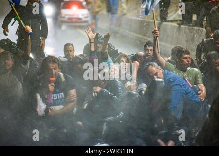 Tel Aviv, Israele. 10 marzo 2024. I manifestanti cantano mentre vengono spruzzati da un cannone d'acqua della polizia durante la dimostrazione. Migliaia di israeliani hanno protestato contro il primo ministro Benjamin Netanyahu e il suo governo di estrema destra chiedendo il rilascio immediato degli ostaggi e le elezioni generali nello Stato di Israele. Durante la manifestazione i manifestanti hanno sfondato le barriere della polizia israeliana e sono iniziati scontri tra la polizia e i manifestanti. (Credit Image: © Matan Golan/SOPA Images via ZUMA Press Wire) SOLO PER USO EDITORIALE! Non per USO commerciale! Foto Stock