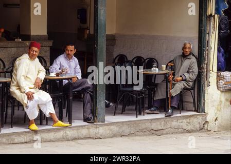 Fez, Marocco - caffetteria nella città Vecchia. I clienti mostrano che gli uomini indossano abiti e scarpe in stile occidentale e tradizionale marocchino. Foto Stock