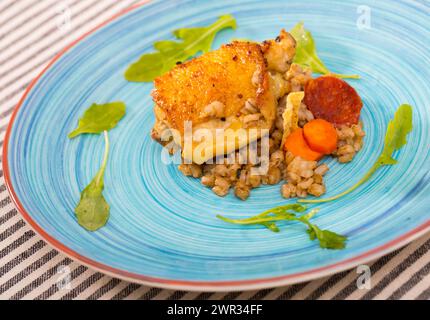 Cosce di pollo al forno con porridge di orzo e rucola Foto Stock