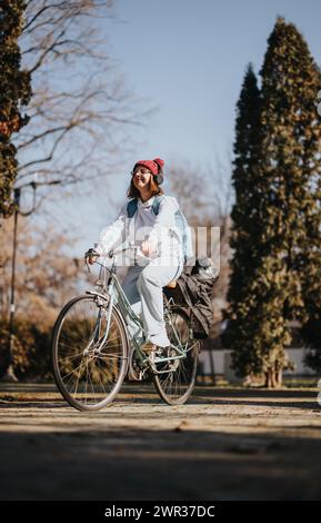 Giovane donna attiva che si gode una giornata invernale di sole su una bicicletta d'epoca nel parco. Foto Stock