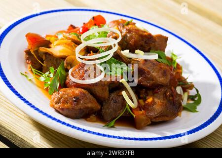 Carne di maiale fritta cotta con peperoni, funghi e cipolla su piatto Foto Stock