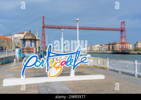 Lettere che identificano la città di Portucalete, sullo sfondo il ponte di Biscaglia sul fiume Nervión. Portugalete-Paesi Baschi-Spagna. 2 marzo, 20 Foto Stock