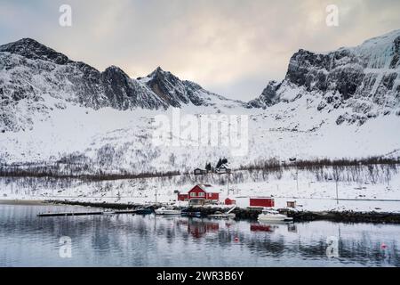 Red Boathouse vicino al fiordo, montagne innevate, Ersfjorden, Senja Island, Norvegia Foto Stock