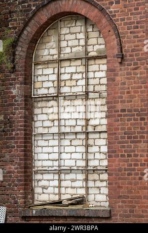 Finestra di mattoni ad arco che è stata murata e mostra la patina Foto Stock