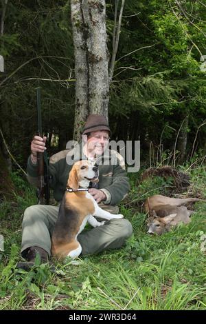 Cacciatore con cane da caccia Beagle che si gode il colpo, anormale capriolo europeo (Capreolus capreolus) Allgaeu, Baviera, Germania Foto Stock