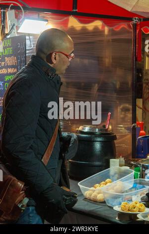 Comprare cibo da un venditore di cibo in una bancarella di mercato a Brick Lane a Londra Foto Stock