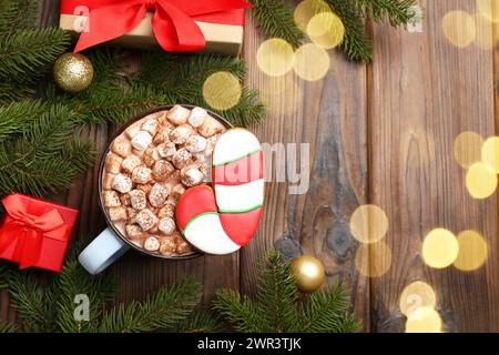 Gustosi biscotti natalizi a forma di canna da zucchero, cacao con marshmallow e decorazioni natalizie su un tavolo in legno, piatto. Spazio per il testo Foto Stock