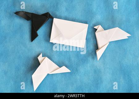 Origami di carta di corvo nero che rubano una lettera di busta bianca da colomba bianca. Concetto di furto di dati e smarrimento di pacchi. Foto Stock