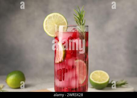Gustoso cocktail di mirtilli con rosmarino e lime in vetro su sfondo grigio, primo piano Foto Stock