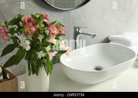 Vaso con bellissimi fiori di Alstroemeria vicino al lavandino in bagno Foto Stock