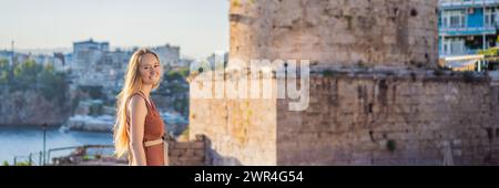 Donna turistica sullo sfondo della Torre Hidirlik di Antalya sullo sfondo della baia mediterranea dell'antico quartiere di Kaleici, Turchia Foto Stock