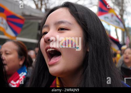 Una dimostratrice pro-tibetana con la bandiera tibetana dipinta sulla sua guancia, canta slogan a Dag Hammarskjöld Plaza vicino all'edificio delle Nazioni Unite durante il 65° giorno della rivolta tibetana. I manifestanti si sono radunati a Manhattan, New York, chiedendo l'indipendenza del Tibet dalla Cina. Il giorno della rivolta tibetana segna il giorno del 1959 in cui migliaia di tibetani in Tibet circondarono il palazzo dell'attuale e XIV Dalai Lama. Il Dalai Lama è il leader spirituale buddista dei tibetani in tutto il mondo. I tibetani circondarono il palazzo nel 1959 per proteggere il Dalai Lama a causa dei timori di un complotto del governo cinese Foto Stock