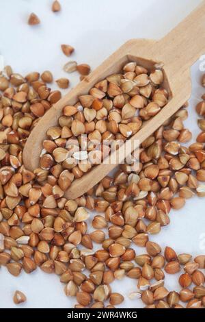 De il grano saraceno mondato con una paletta in un recipiente bianco, isolato su bianco Foto Stock