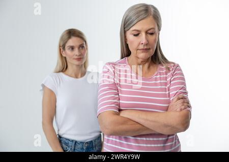 Mamma in piedi con le braccia incrociate, sua figlia dietro di lei Foto Stock