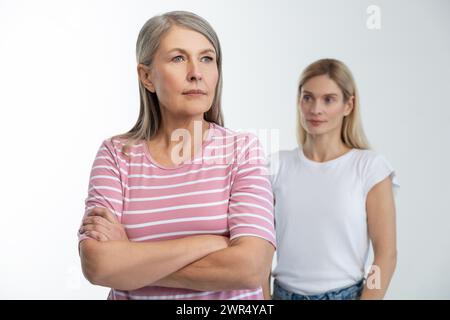 Mamma in piedi con le braccia incrociate, sua figlia dietro di lei Foto Stock