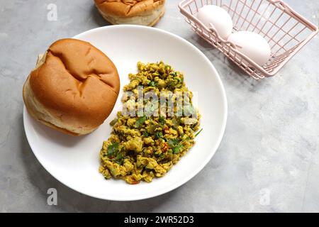 Anda Masala Bhurji o uova strapazzate indiane piccanti con pane o Bun Pav, un popolare cibo di strada a Mumbai. Serviti in un piatto bianco con spazio per le copie Foto Stock