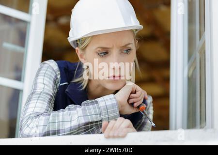 lavoratore edile che utilizza un cacciavite sul telaio della finestra Foto Stock