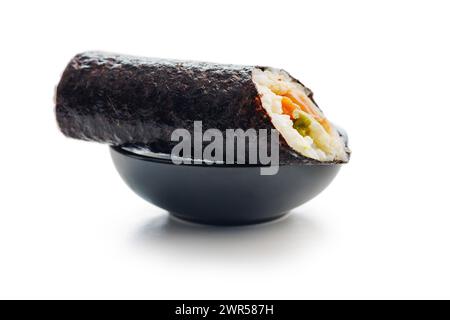 Un sushi roll tagliato a fette e esposto con un lato di salsa di soia salata. Il sushi offre pesce fresco, riso e verdure arrotolate in alghe, mentre Foto Stock