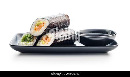 Un sushi roll con riso, alghe e vari ripieni disposti in modo ordinato su un piatto nero, accompagnato da una ciotola di salsa di soia. Foto Stock