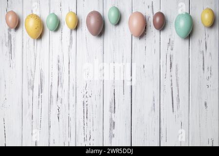 Uova di Pasqua multicolore su sfondo bianco invecchiato in legno vintage. Copia spazio Foto Stock